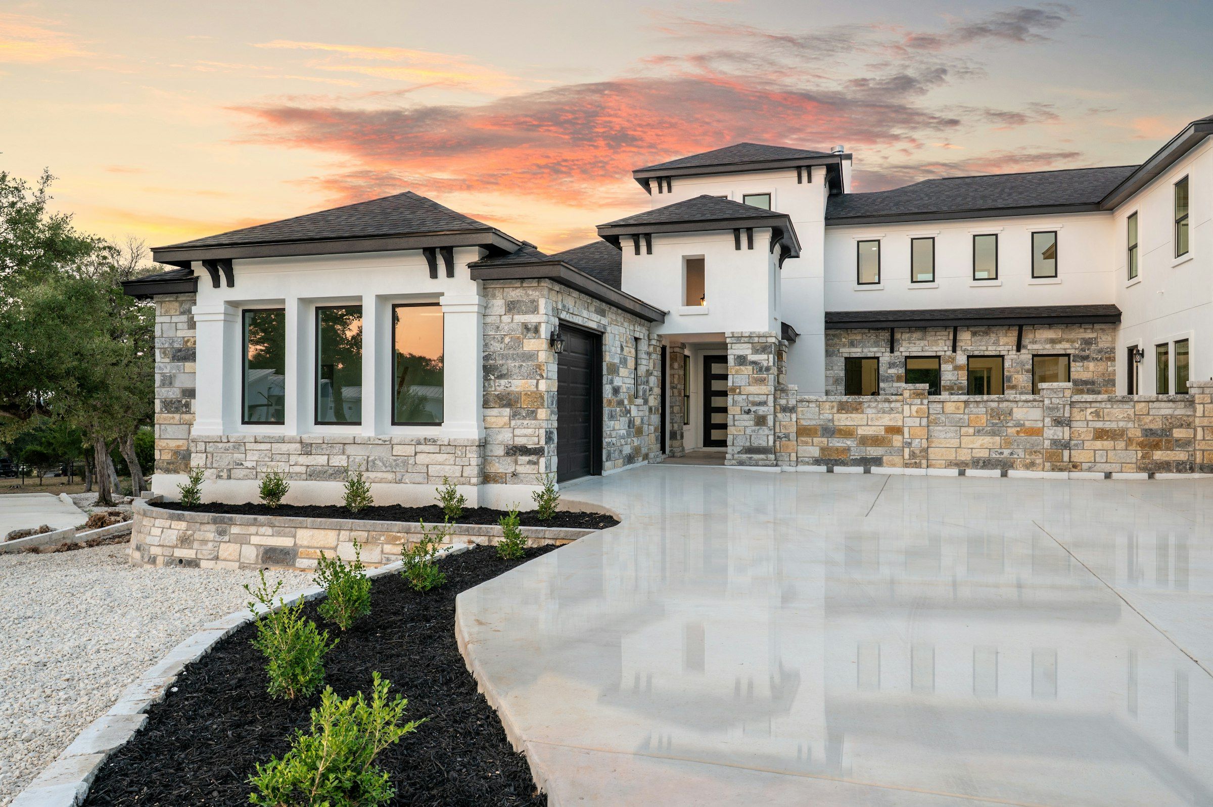 Stone and stucco custom home exterior at sunset, new construction