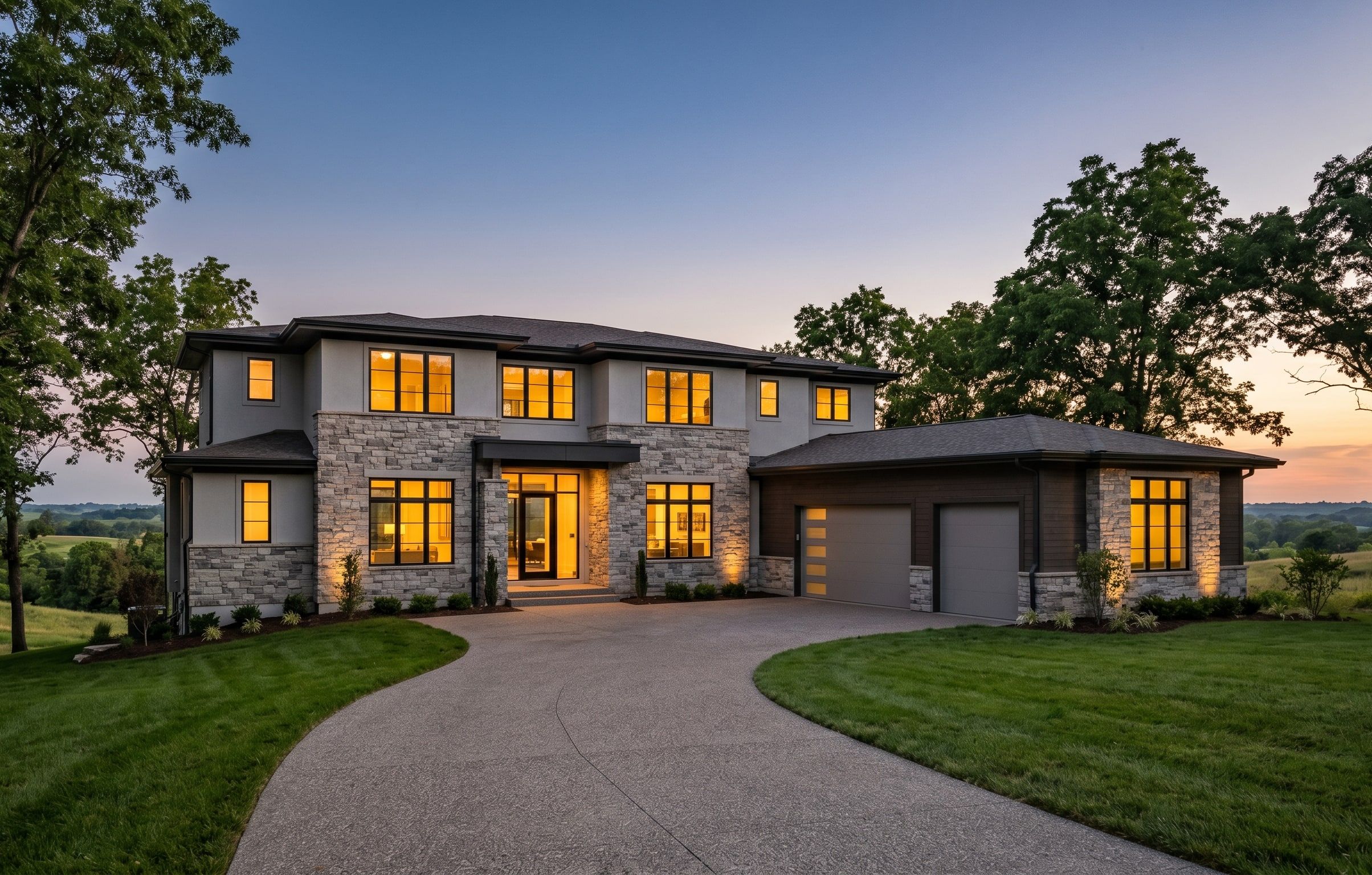 Luxury custom home exterior at dusk with warm lit windows