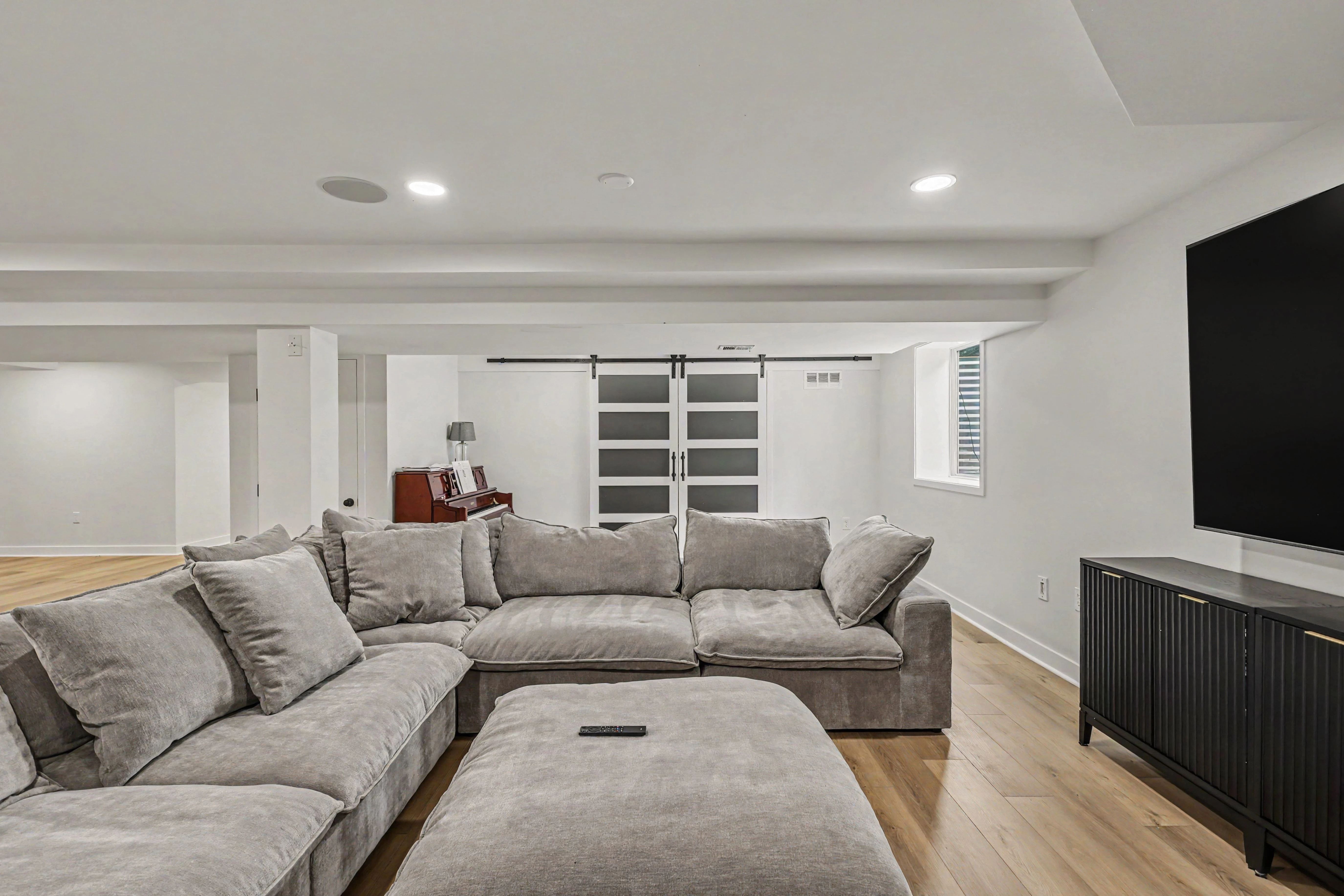 Finished basement family room with sectional, barn doors, and piano nook from a Prairie Village basement remodel