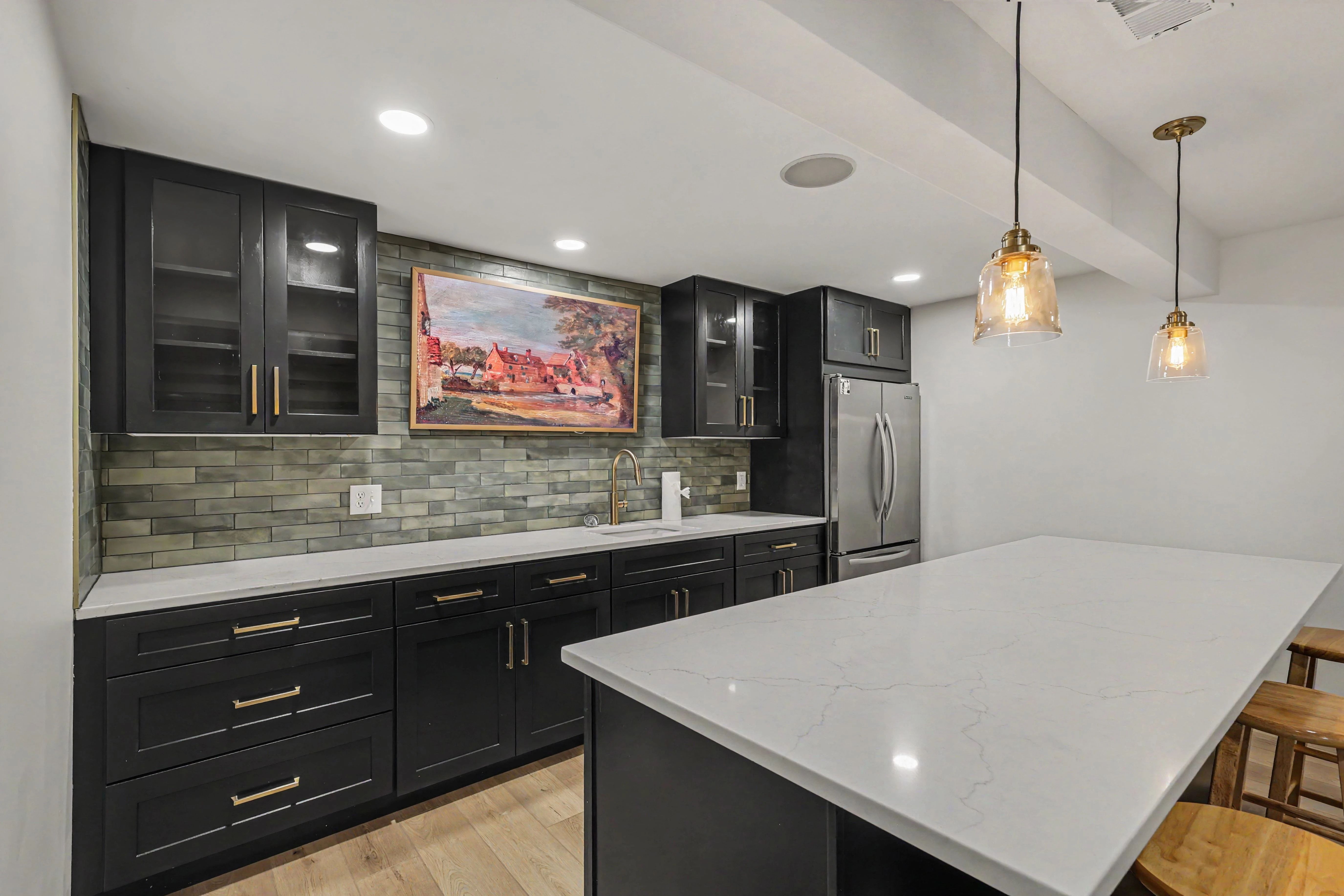 Black shaker cabinetry with brass hardware and quartz counters in a Prairie Village basement remodel kitchenette